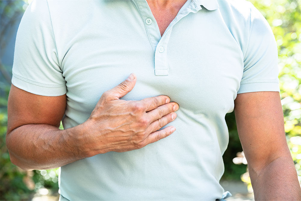 A man experiencing acid reflux presses his hand to his chest.