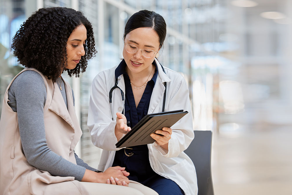 A genetic counselor points at results on a clipboard in front of a woman.